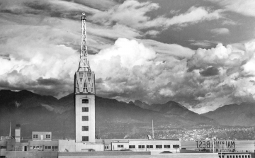 Black and white photo of the Woodward’s Department Store searchlight atop the tower. Circa 1938. North Shore mountains in the background.
